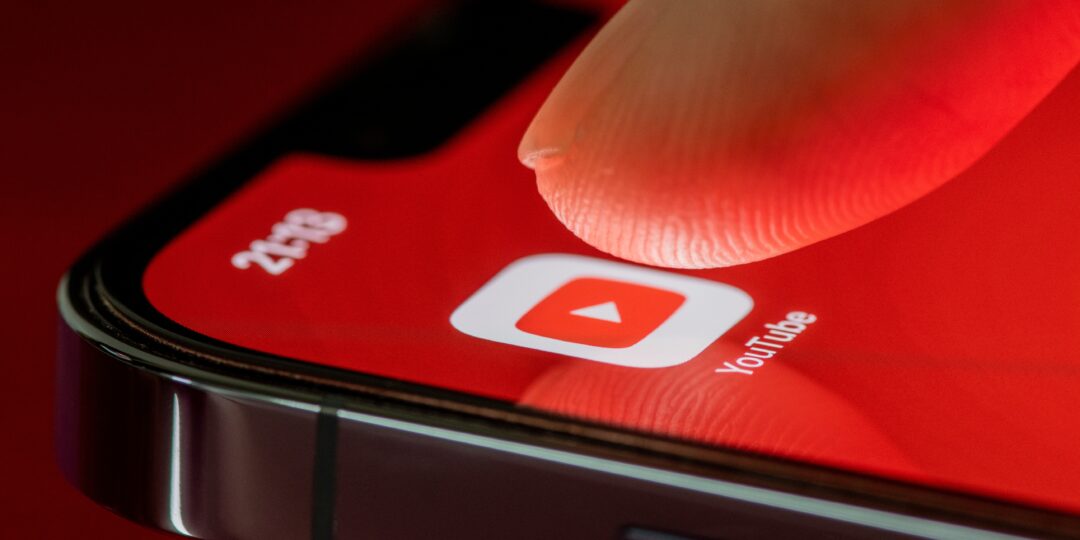 finger pressing on youtube icon on smartphone